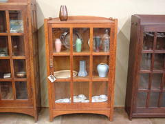 Shown between a Gustav Stickley arched china cabinet to the left and an early mitered-mullion bookcase to the right.